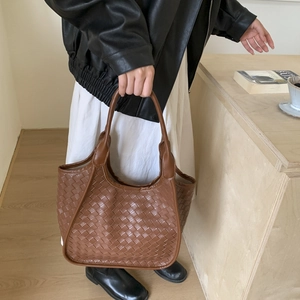 Detailed view of brown woven tote bag with Intrecciato pattern and smooth leather handle