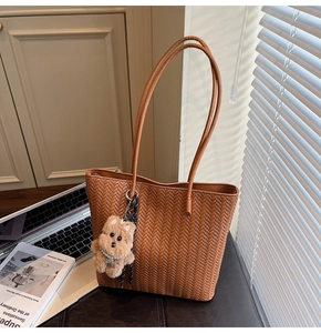 Detail of vintage brown woven leather tote bag with cute plush puppy charm accessory