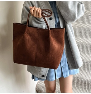Detail of large dark brown suede tote bag featuring fine velvet texture and slim handles