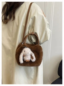 Detail einer braunen Plüschhandtasche mit süßem weißen Hasenanhänger und Ledergurt