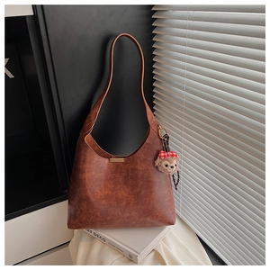 Detail of vintage brown leather bucket bag with magnetic clasp and plush bear charm
