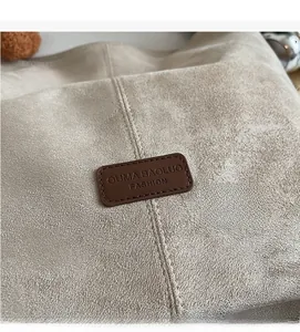 Nahaufnahme der beigen Wildleder-Tote-Bag mit aufgenähtem braunem Lederlogo von OUMA BAOLUO