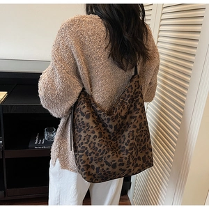 Detail of large leopard print hobo bag showing suede texture and minimalist black strap