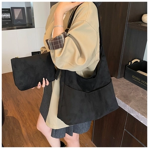 Dettaglio della borsa tote in pelle scamosciata nera con pochette e outfit elegante