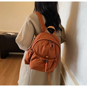 Caramel nylon backpack detail featuring unique pleated texture and drawstring front pocket