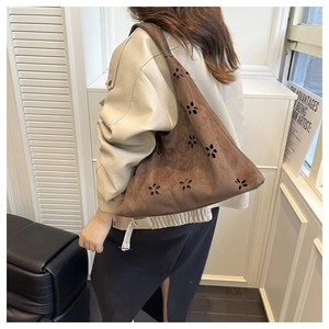 Détail du sac Hobo marron foncé en daim mat avec des découpes florales au laser