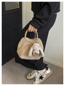 Detailansicht der beigen Plüschhandtasche mit Hasenanhänger und braunem Ledergriff