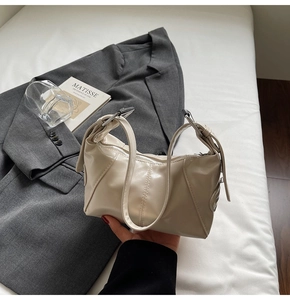 Detail of beige faux leather shoulder bag with adjustable silver buckle on a blazer