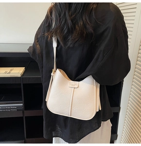 Detail view of cream bucket bag showing lychee grain leather and fashion trend label