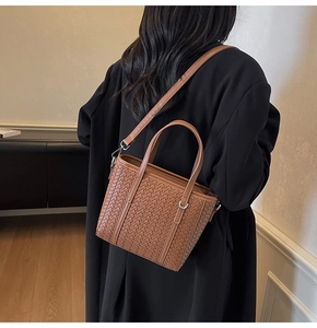 Detail of woven leather bucket bag in caramel brown showing texture and strap