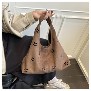Détail du sac cabas vintage en daim marron avec des motifs floraux découpés au laser