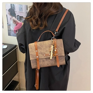 Détail d'un sac bandoulière vintage marron avec sangles décoratives et pompon en perles colorées