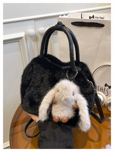 Nahaufnahme der schwarzen Kunstfell-Handtasche mit grauem Hasenanhänger und Ledergriffen