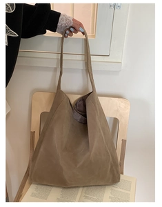 Close-up of a large khaki tote bag made of high-quality nubuck leather on a wooden chair