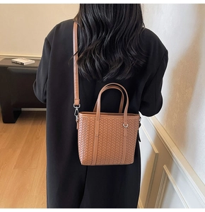 Rear view of a model wearing the caramel woven bucket bag with shoulder strap