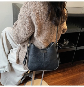 Detail of black pebbled leather bucket bag with gold hardware and fashion buckle closure