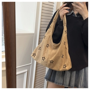 Sac cabas marron en daim avec motifs floraux découpés au laser montré dans un miroir
