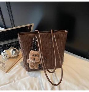 Brown woven tote bag detail showing large capacity with laptop and bear charm