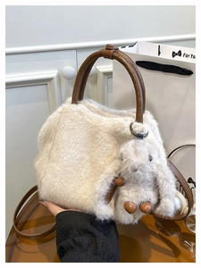 Detail der cremefarbenen Plüschtasche mit braunen Ledergriffen und Hasen-Anhänger