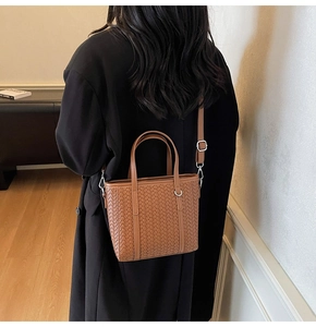 Detail view of brown woven bucket bag featuring refined texture and leather shoulder strap