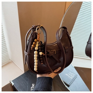 Detail of dark brown hobo bag featuring decorative wood beads and vintage metal buckle