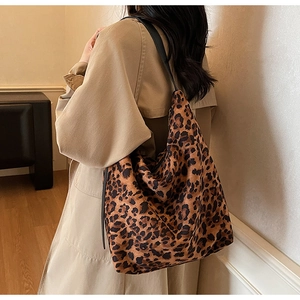 Detail of large leopard print bucket bag on shoulder with sleek black straps