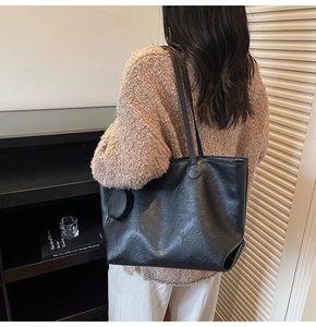 Detail of black leather tote bag featuring a round zip coin purse and gold lettering
