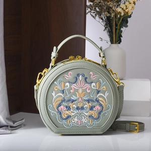Detailed embroidery of classical floral patterns on sage green round crossbody bag