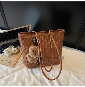 Close-up of brown woven tote bag with cute teddy bear charm and silk ribbon detail