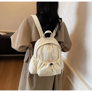 Close-up of lightweight off-white nylon backpack featuring drawstring pocket and dual zippers