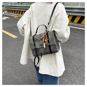Détail d'un sac à bandoulière gris texturé avec pendentif en perles de bois colorées