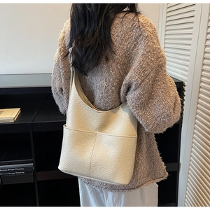 Detail view of large beige hobo bag with pebble leather texture and dual front pockets