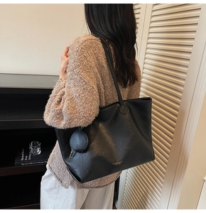 Detail of black PU leather tote bag with logo print and matching small round pouch