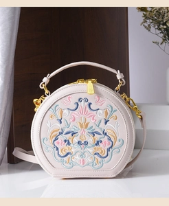 Detailed view of floral embroidery on pink leather bag with gold-tone hardware