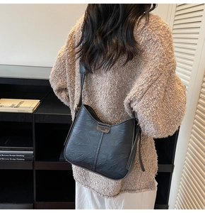 Détail du sac seau vintage noir avec bandoulière ajustable porté par un mannequin en décor moderne
