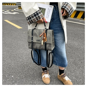 Détail d'un sac à dos vintage gris foncé avec lanières en cuir et charme en perles de bois