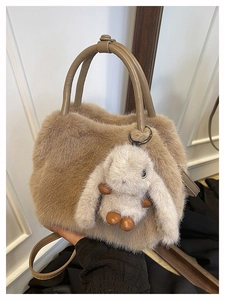 Detail einer braunen Kunstfell-Tasche mit flauschigem Hasen-Anhänger und Lederriemen