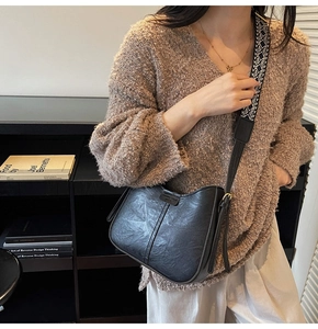 Close-up of black retro bucket bag with a geometric pattern woven shoulder strap