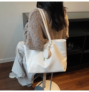 Detail of a creamy white large tote bag featuring natural pleated texture and a round coin purse