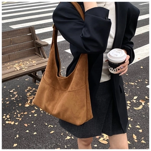 Borsa tote in pelle scamosciata marrone con ampia tracolla in un contesto urbano autunnale