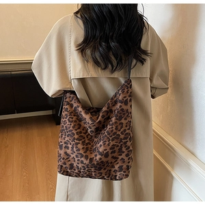 Detail shot of a large leopard print bucket bag on a model wearing a beige trench coat