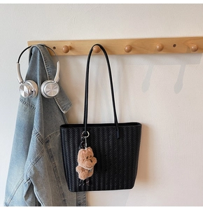 Detail of black woven tote bag with a cute brown teddy bear plush charm and pearls