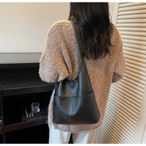 Close-up of black litchi grain leather tote bag with wide external pocket and shoulder strap