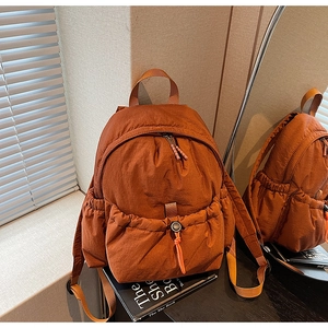 Detail of caramel nylon backpack featuring drawstring pocket and durable fabric texture