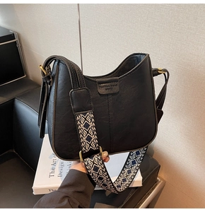Close-up of black leather bucket bag with geometric jacquard wide shoulder strap