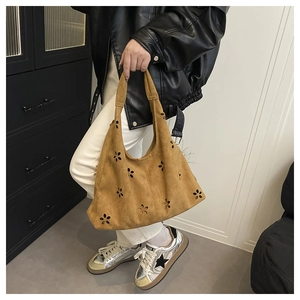 Détail du sac cabas vintage en daim marron avec motifs floraux découpés au laser