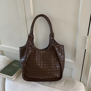 Close-up of deep brown woven leather texture on a stylish bucket tote bag
