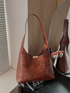 Brown vintage textured bucket bag with plush charm and golden magnetic closure