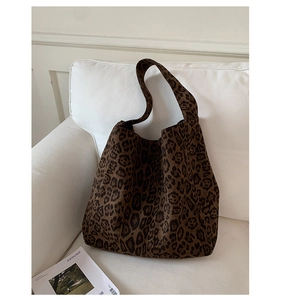 Detail of leopard print tote bag with thick fabric strap resting on a white sofa