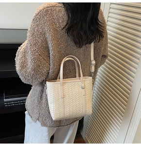 Detail view of cream woven bucket bag with silver hardware and adjustable strap